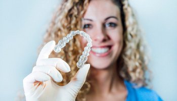 Orthodontic team member holding clear aligner in gloved hand